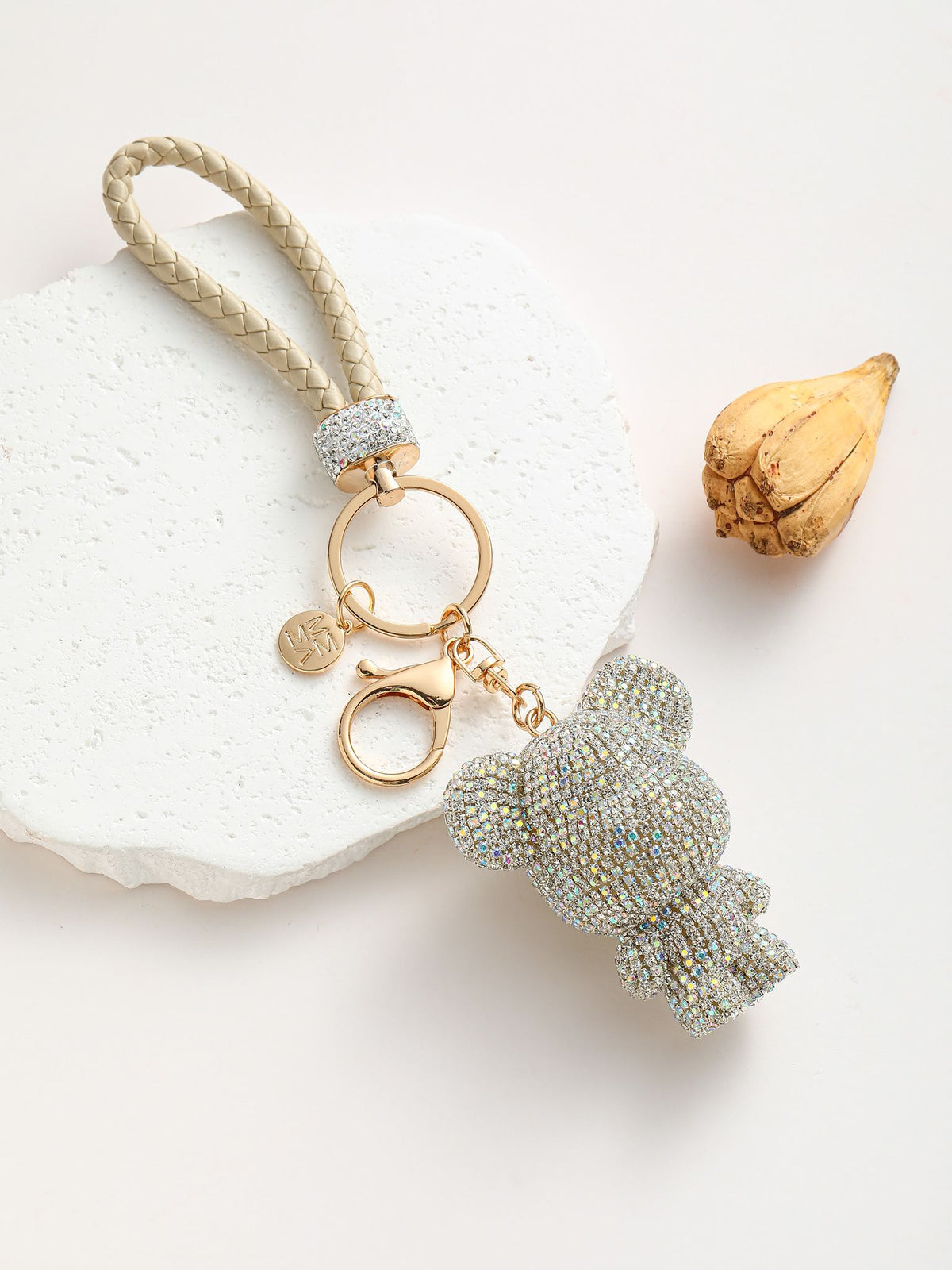 Portachiavi composto da un anello dorato su cui si agganciano due componenti: un adorabile orsetto completamente ricoperto di strass colorato e un manico intrecciato in pelle sintetica.