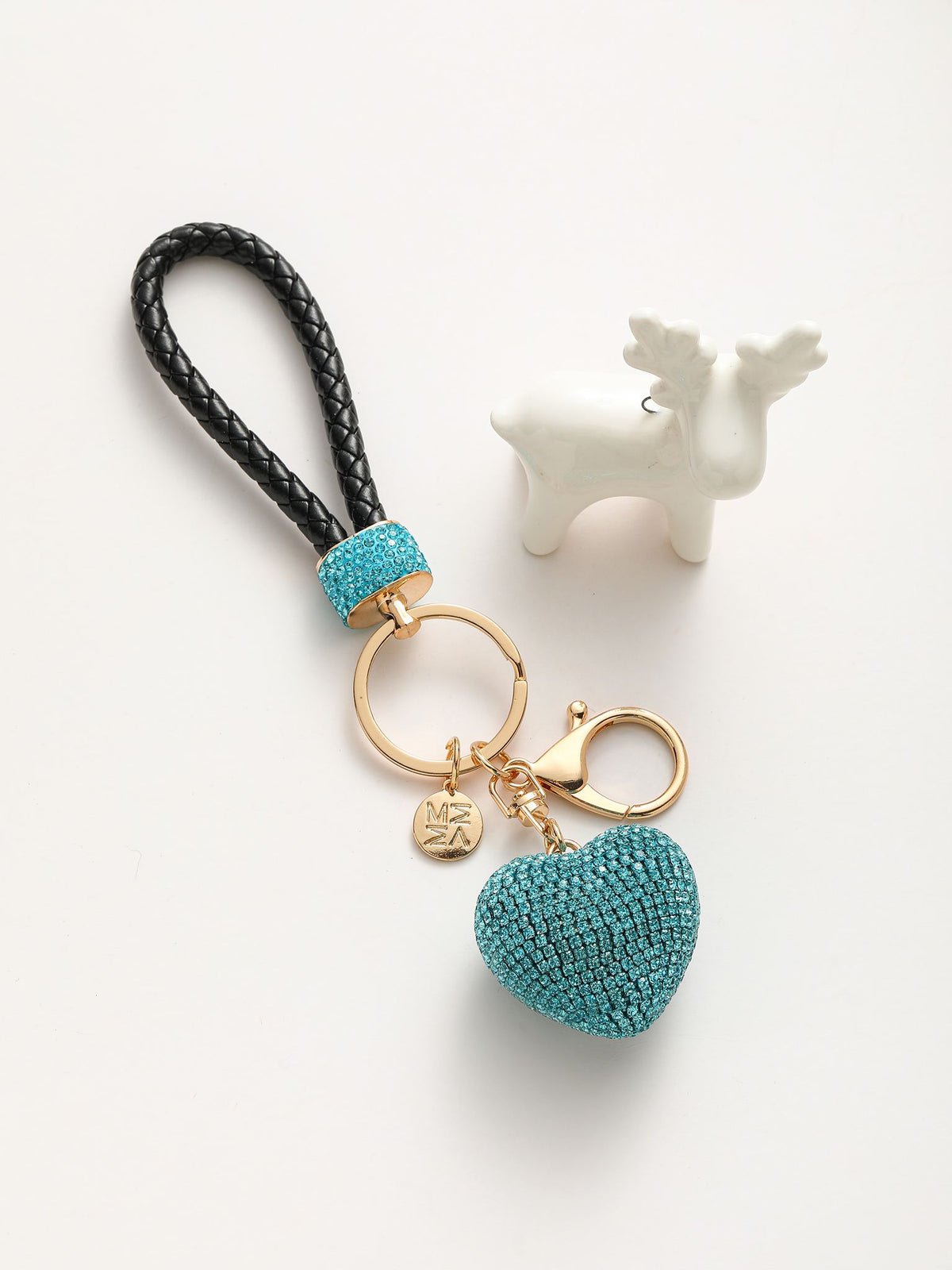 Portachiavi composto da un anello dorato su cui si agganciano due componenti: un cuore tridimensionale completamente ricoperto di strass colorato e un manico intrecciato in pelle sintetica.
