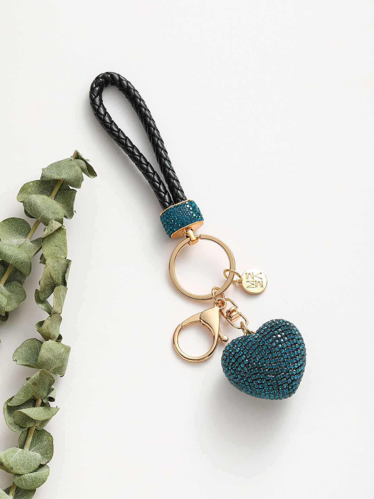 Portachiavi composto da un anello dorato su cui si agganciano due componenti: un cuore tridimensionale completamente ricoperto di strass colorato e un manico intrecciato in pelle sintetica.